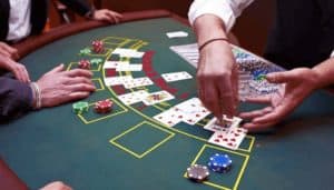Blackjack table and hands of dealer and player playing a variation of blackjack.